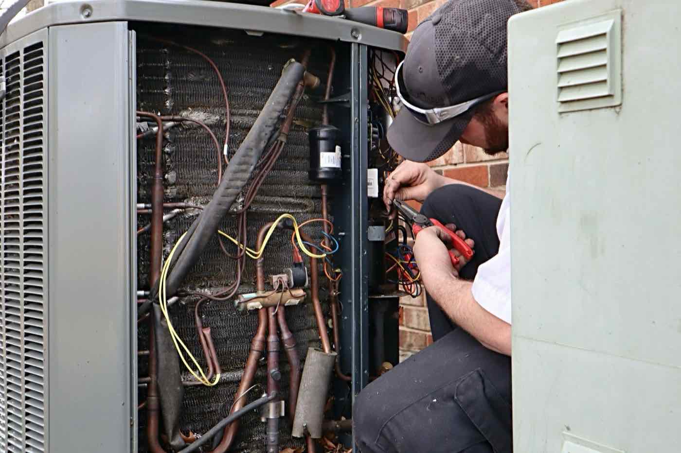 A My AC Guy technician working on the wiring inside an outdoor AC unit.