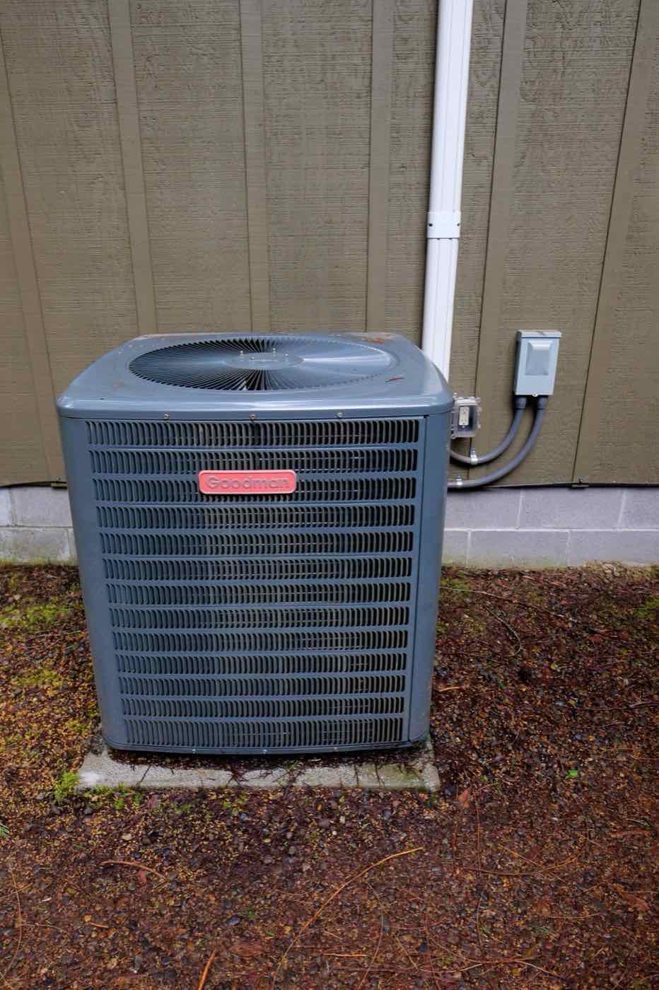 An outdoor AC unit installed beside a house.